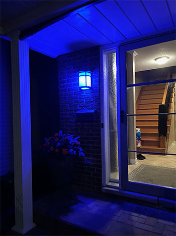 The porch of a home at night, illuminated by a blue light